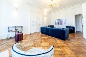 a living room with a blue couch and wooden floors at Gîte Vosges en Ville luxueux appartement Duplex avec sauna espace bien être au centre d'Epinal in Épinal