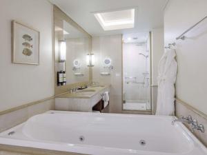 a large white bathroom with a tub and a sink at Pullman Reef Hotel Casino in Cairns