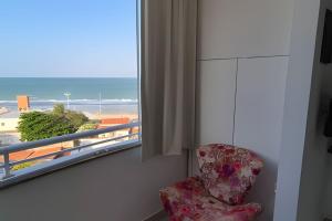 een stoel naast een raam met uitzicht op het strand bij Apartamento Brisa do Mar in Natal