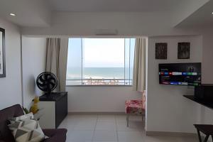 a living room with a large window with a view of the ocean at Apartamento Brisa do Mar in Natal