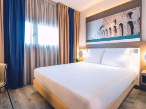 a hotel room with a large bed and a window at Mercure Roma Centro Colosseo in Rome +60 photos