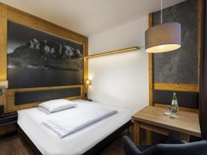 Un dormitorio con una cama, un escritorio y una lámpara. en Mercure Hotel Garmisch Partenkirchen, en Garmisch-Partenkirchen