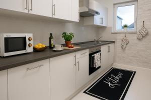 a kitchen with white cabinets and a black rug at Black Forest Oase in Gaggenau