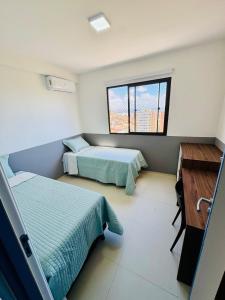 a bedroom with two beds and a desk and a window at apartamento com vista para o mar in Aracaju +19 photos
