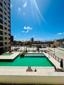 a swimming pool with green water in a city at apartamento com vista para o mar in Aracaju