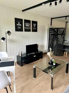 a living room with a piano and a glass table at Studio cosy à Métabief in Métabief