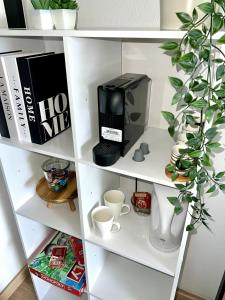 a white book shelf with a coffee maker and cups at Studio cosy à Métabief in Métabief