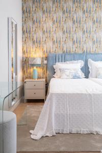 a bedroom with a white bed and a blue wall at Casa Graminho in Ponta do Sol