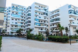un gran edificio de apartamentos con palmeras enfrente en Ocean Park Sunset Escape beach front with swimming pool, en Aïn Harrouda