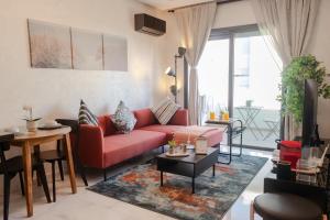 Una sala de estar con un sofá rojo y una mesa. en Ocean Park Sunset Escape beach front with swimming pool, en Aïn Harrouda