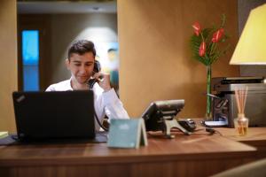 a man talking on a phone at a desk with a laptop at Ada Suites Nisantasi in Istanbul