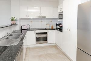 a white kitchen with a sink and a stove at Beachfront Canvas - Ocean Views Pool Gym in Mudjimba