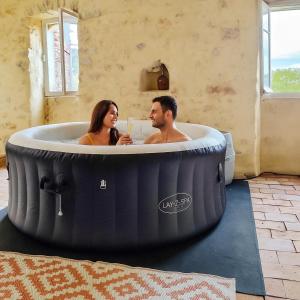 ein Mann und eine Frau sitzen in einer großen Badewanne in der Unterkunft Le mazet des Galinières in Allegre Les Fumades
