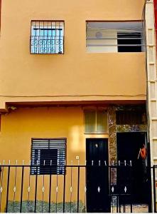 a building with a black door and a fence at Hotel America Apartments in Dakhla