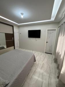 a bedroom with a bed and a flat screen tv at Casa de 4 Quartos - 2 suites in Ananindeua