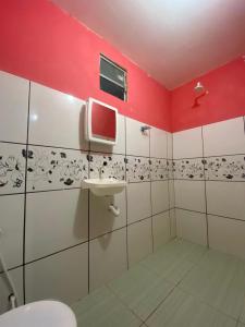 ein Badezimmer mit einem Waschbecken und einer roten Wand in der Unterkunft Pousada Brilho do Mar in Guriú