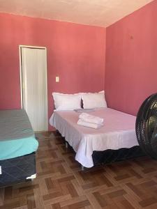 1 Schlafzimmer mit 2 Betten mit rosa Wänden und Holzböden in der Unterkunft Pousada Brilho do Mar in Guriú