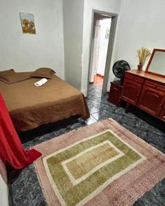 een slaapkamer met een bed, een tafel en een tapijt bij Cantinho dos Barbosas in Angra dos Reis