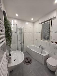 a bathroom with a tub and a sink and a toilet at FlexHome Stadtnatur Ferienwohnung in Lippstadt