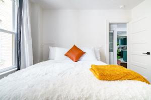 a bedroom with a white bed with an orange pillow at Prime Location Top Rated Clean Parking Free! in Columbus +52 photos