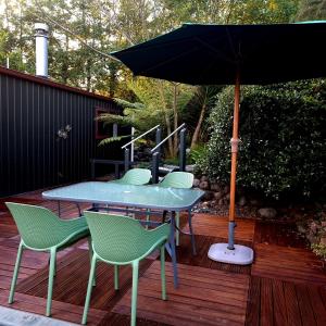 a table with chairs and an umbrella on a deck at Swiss-Kiwi Cottage and Retreat, B&B in Tauranga