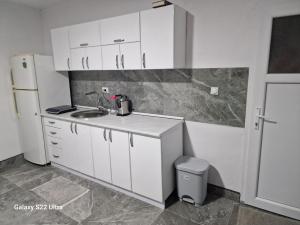 cocina con armarios blancos, fregadero y nevera en Apartmani Kruče, en Ulcinj