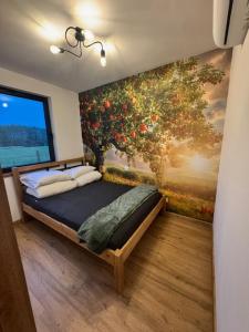a bedroom with a painting of a fruit tree at Agroturystyka Rajska Jabłoń in Maków