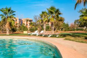 a pool with two picnic tables and palm trees at Dar Dmana Luxury Apt Pools, Tennis & Private Garden in Dar Caïd Layadi