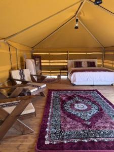 a room with a bed and a rug in a tent at Desert Vibes Camp in Bidiyah +12 photos