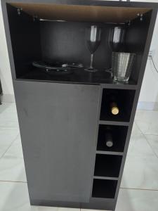 a wine cabinet with two wine glasses on it at Flat completo a 17 minutos do campo do Goiás in Aparecida de Goiania