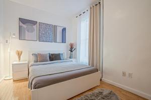 a white bedroom with a bed and a window at Warm and Welcoming 2BR in Upper East Side in New York