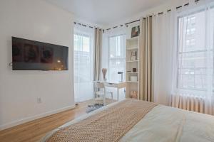 a white bedroom with a bed and a desk at Warm and Welcoming 2BR in Upper East Side in New York