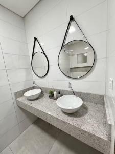a bathroom with two sinks and a mirror at Estadia Incrível Aconchego e Praticidade Juntas in Lucas do Rio Verde