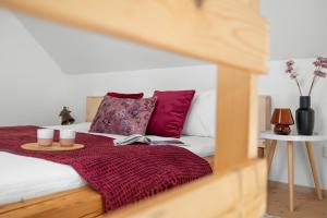 a bed with red pillows and a red blanket at Statek Luigi in Tuchlovice