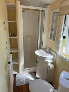 a small bathroom with a toilet and a sink at Seaside Getaways Caravan Hire in Chapel Saint Leonards +47 photos