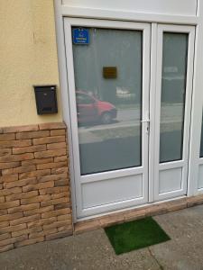 a door to a building with a red car reflected in the window at Apartman Nevena in Subotica
