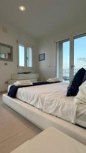 a large white bed in a room with windows at Blue Tao Maison Taormina in Taormina