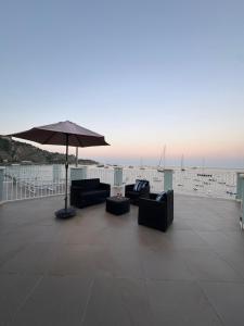 a patio with two couches and an umbrella at Blue Tao Maison Taormina in Taormina