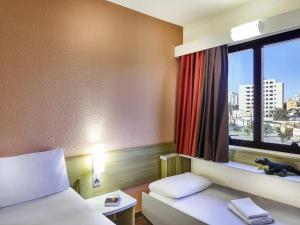 a hotel room with a bed and a window at ibis Taubate in Taubaté +69 photos