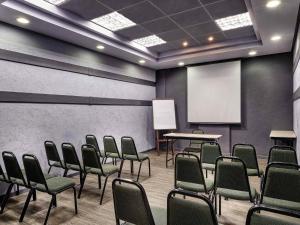 a conference room with chairs and a white screen at ibis Taubate in Taubaté