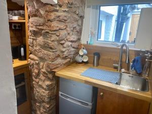 a kitchen with a sink and a stone wall at Cosy cottage in Torquay +24 photos