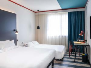 a hotel room with two beds and a desk at ibis Styles Barcelona Sant Joan Despi in Sant Joan Despí +104 photos
