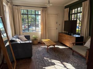 ein Wohnzimmer mit Sofa und Fernseher in der Unterkunft Oatlands Cottages in Grahamstown