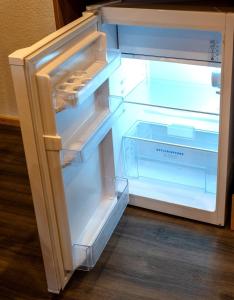een lege koelkast met de deur open op een houten vloer bij Gemütlichkeit in Heltersberg