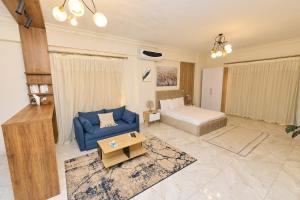 Una sala de estar con un sofá azul y una cama. en Settle Inn South 90 Apartments, en El Cairo