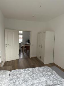 a white bedroom with a bed and a dining room at Wupper Apartments Vogel in Erbschlö +4 photos