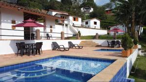 a pool with chairs and a table and a house at Aires de Encanto in Curití