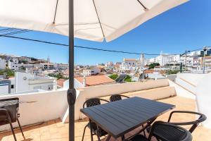 a table and chairs on a balcony with an umbrella at Casa Malpique in Albufeira