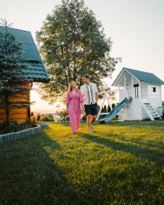 a man and a woman walking through a yard with a slide at Willa Paula in Ząb +161 photos