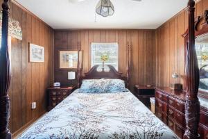 una camera da letto con un letto con pareti rivestite in legno di LaRue's Private Lakeside Cottage ad Abbeville
